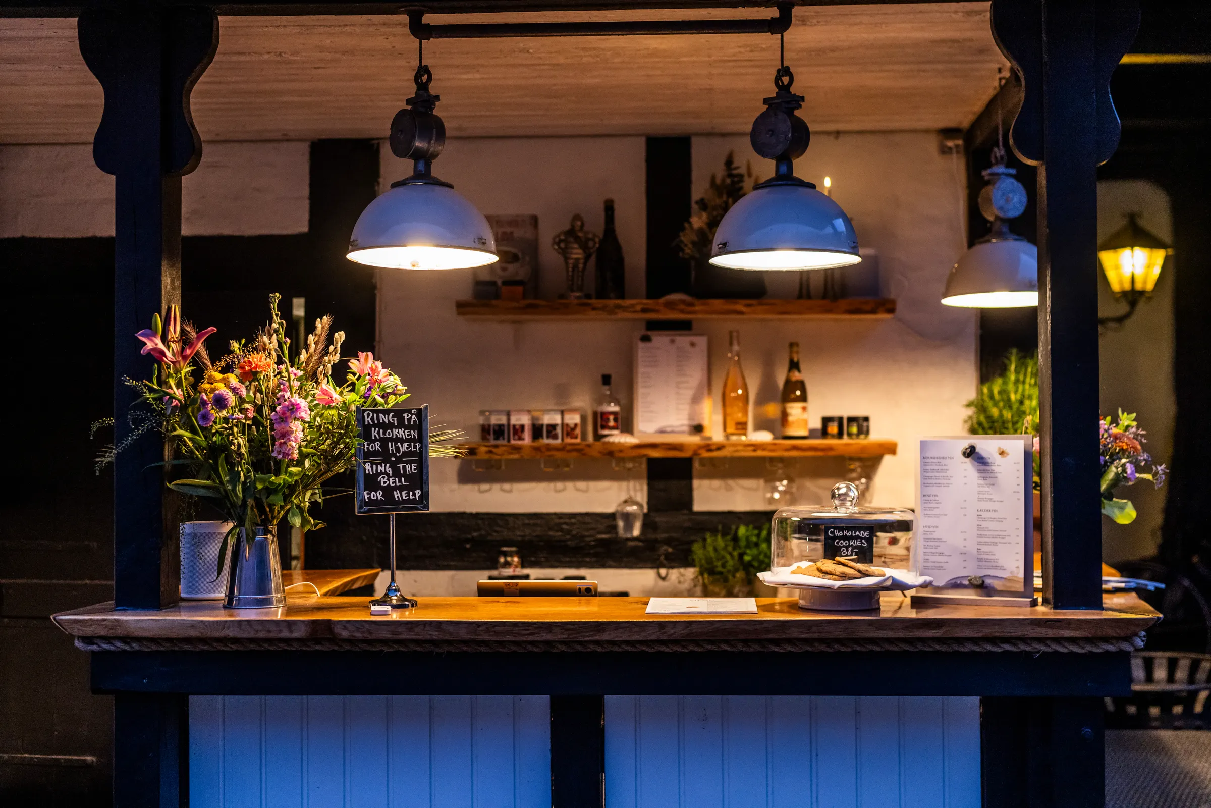 Die Byskriverbar im Allinge Badehotel am Abend, mit Blumen und Menütafel